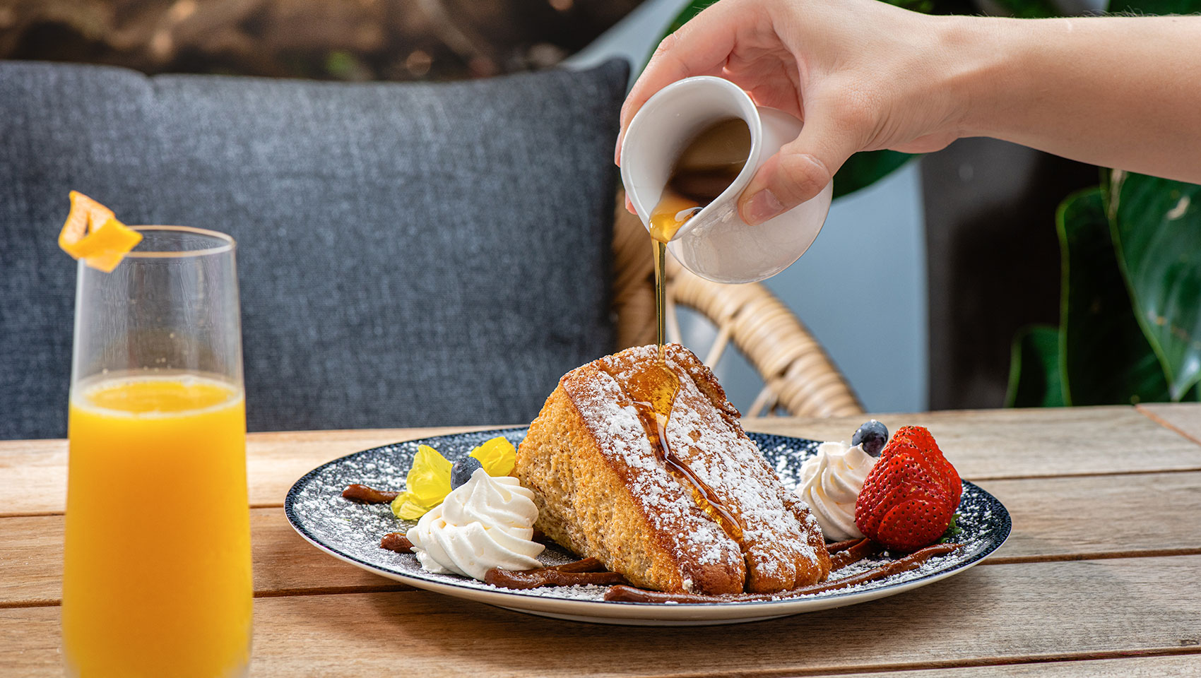 a person pouring syrup on a plate of food