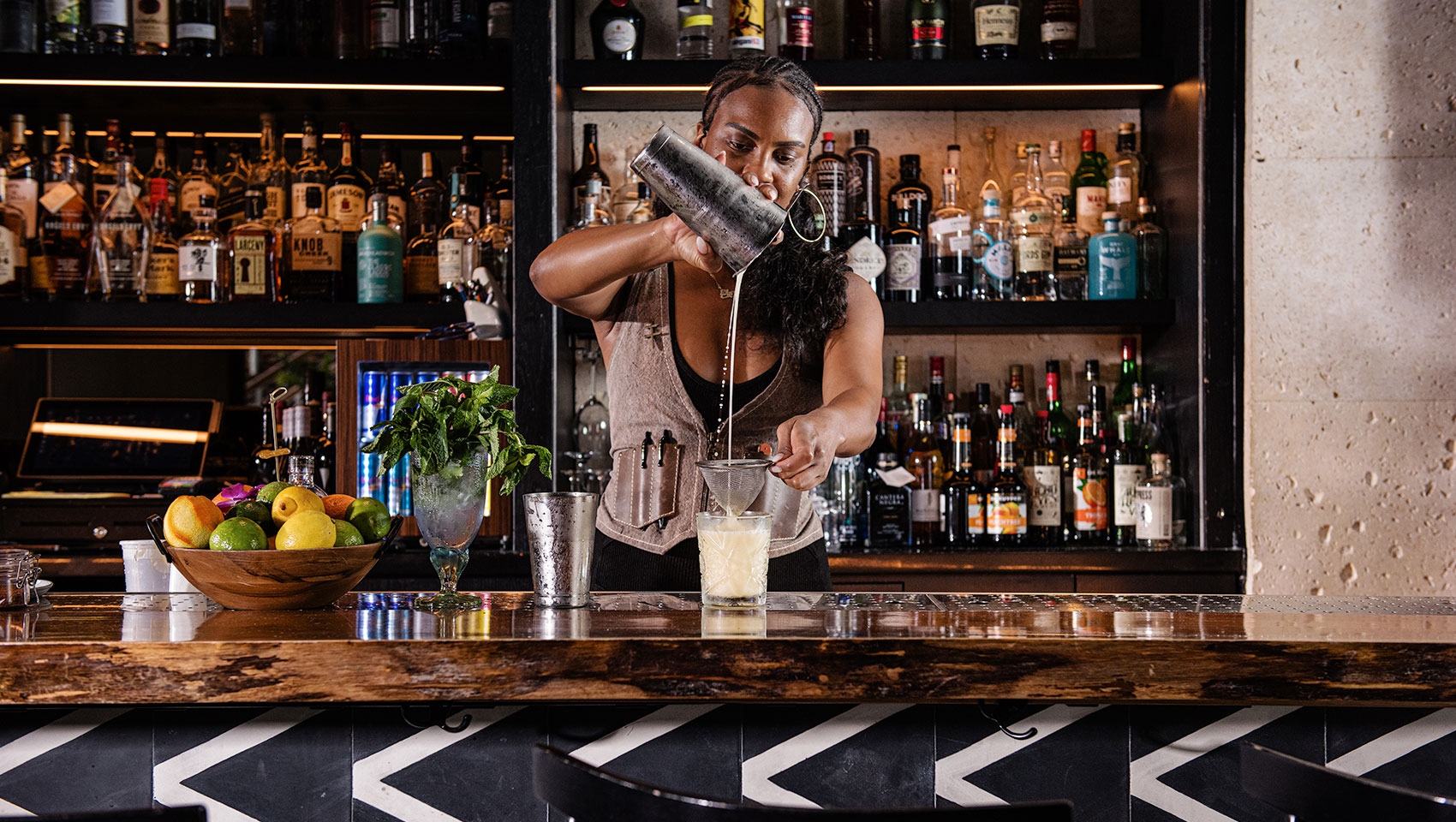 a bartender pouring a drink into a glass