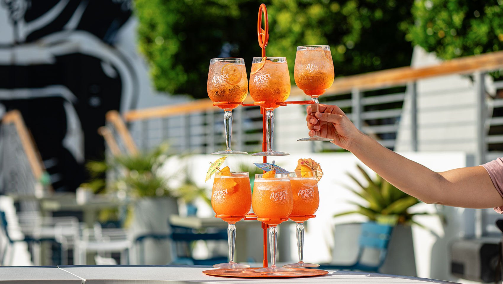 a hand holding a pyramid of glasses with orange liquid